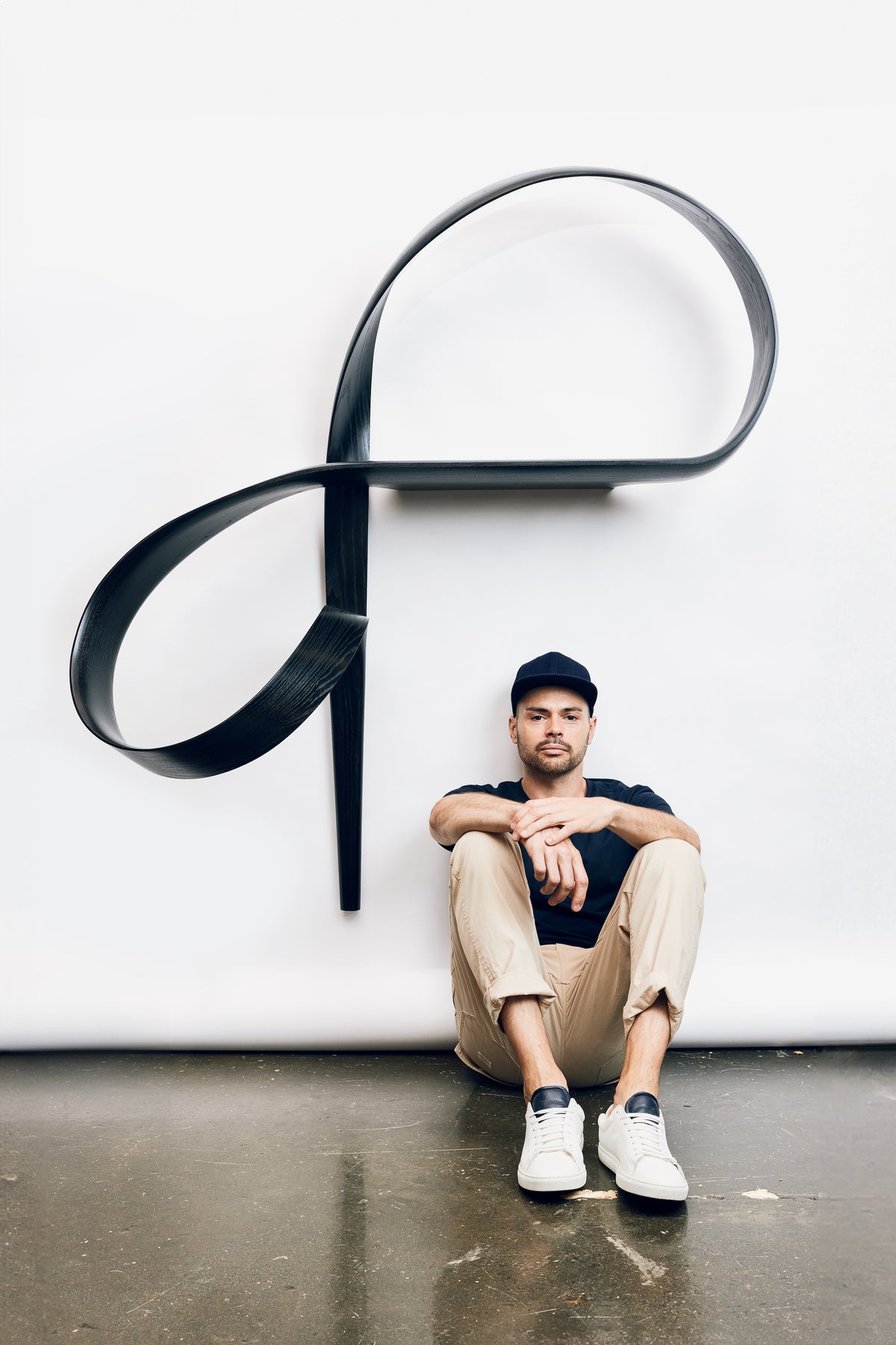 Adam Bentz’s Emovere Display Shelf installed on a wall with a seated person for scale