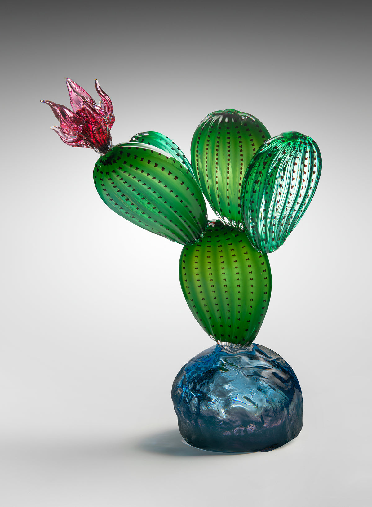 Nopal Frío, glass prickly pear cactus sculpture with a magenta blossom on a blue glass base by Manolo Aguilera